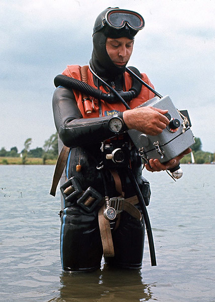 Pionierski fotograf podwodny Colin Doeg dzierży specjalnie zbudowaną obudowę aparatu Bronica w żwirowni w latach 1960. XX wieku.