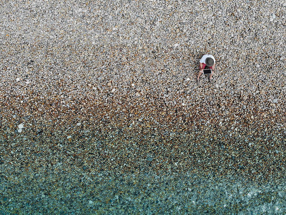 Drone Picture of a guy using apple tablet at the beach