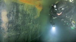 Extreme underwater filming footage showing Andy Torbet next to 1938 mining foreman names and tally marks, filmed by Rich Stevenson