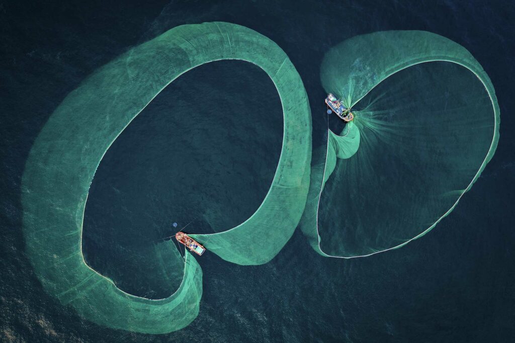 Previous winner Big Appetite by Thein Nguyen Ngoc, an aerial shot showing boats straining Vietnamese  waters for anchovies
