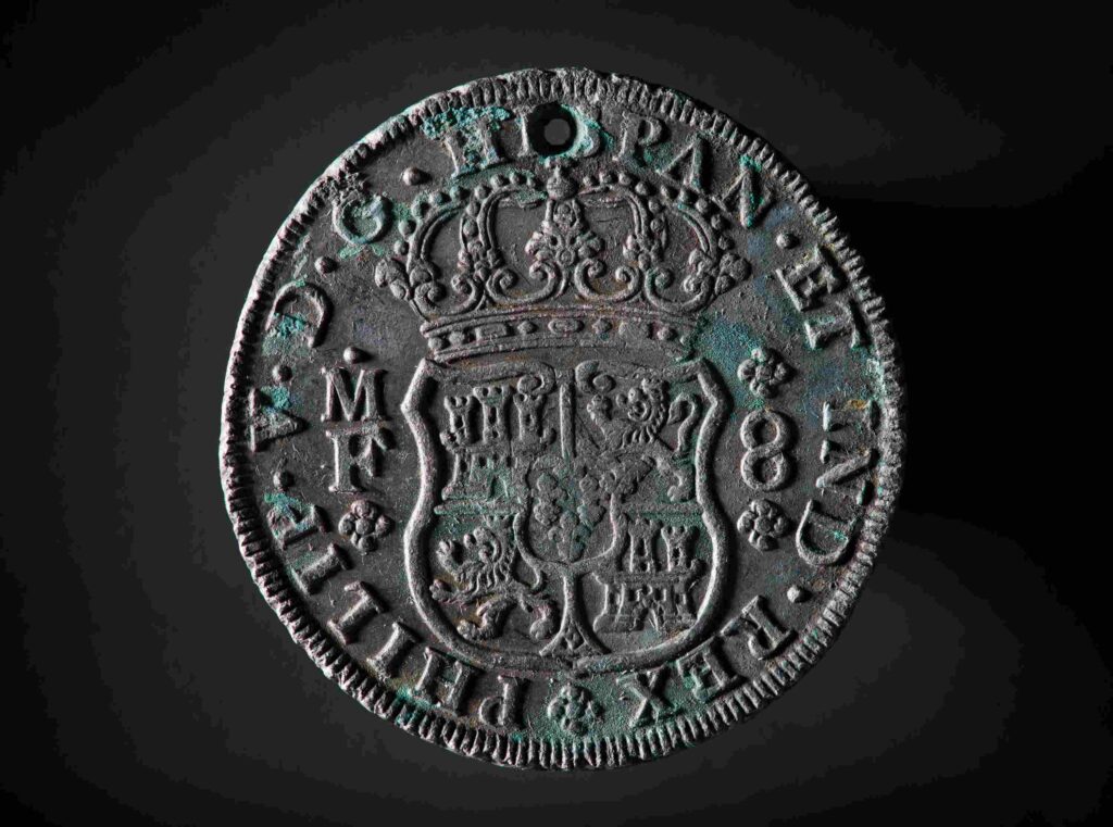 A Pillar dollar, 8 reals and minted in Mexico. At the top there is a small hole, this hole was probably made to sew to the coin into the clothes of crewmembers to smuggle the money to the Dutch East Indies