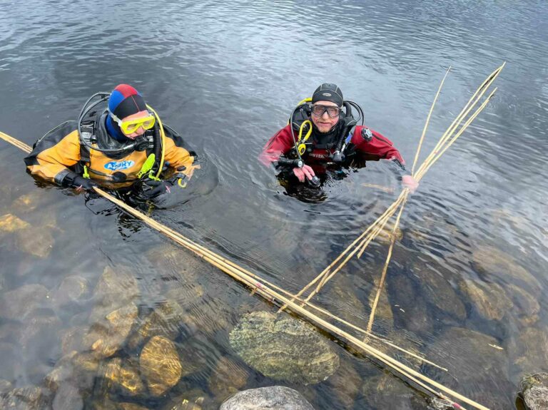 Richard Guest and Duncan Ross preparing to place garden canes around the base of a crannog to take measurements (Elizabeth Blackburn)