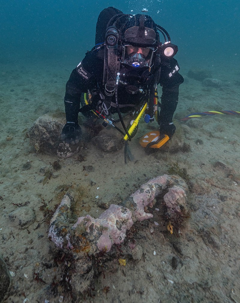 Parks Canada underwater archaeology technician Joe Boucher examines one of Erebus’s ice anchors, discovered in 2023 in the debris field (Brett Seymour / Parks Canada)