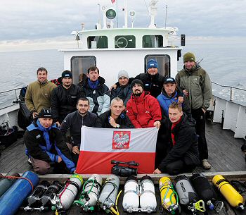 The dive team on the deck of Nitrox, displaying the Polish Navy flag