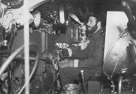 Dentro de um submarino anão X-Craft, olhando para trás, com um oficial na posição de controle posterior