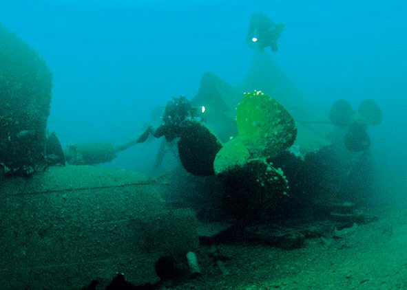 Een duiker geeft schaal aan een van de grote propellers die de HMS Audacious met een snelheid van wel 21 knopen voortbewoog