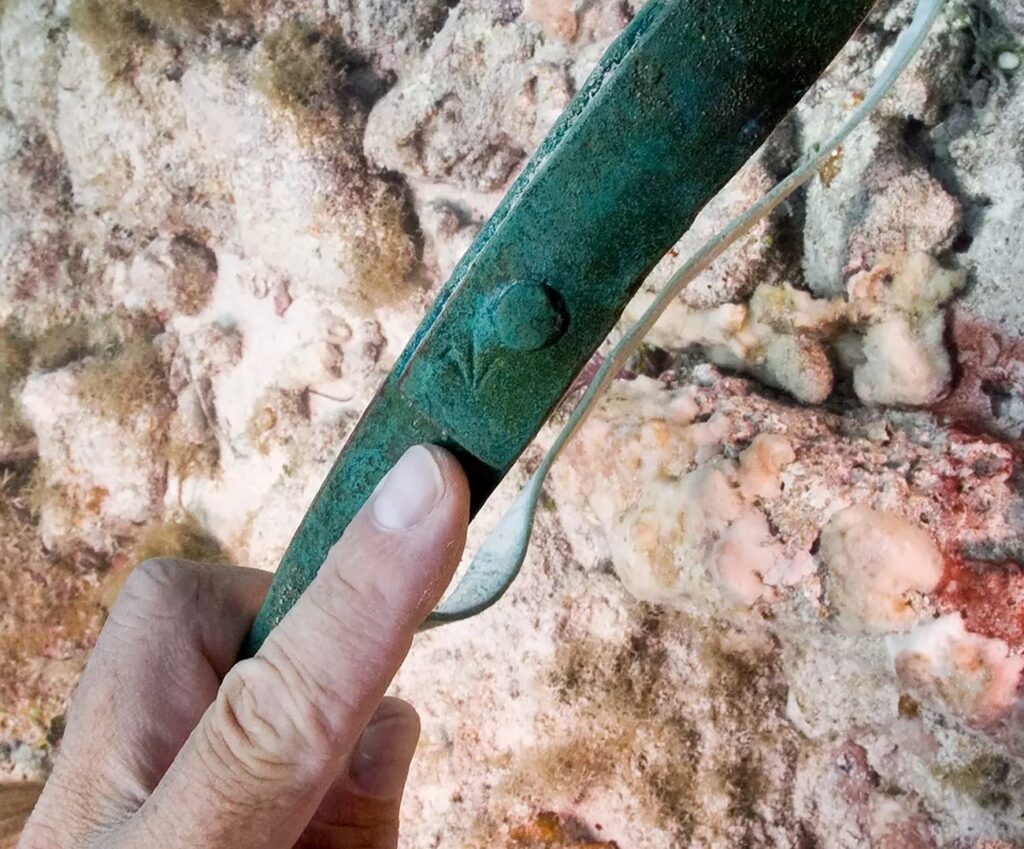 潜水员辨认出铜桶带上的宽箭头标记，表明它是 18 世纪的英国军事财产（Brett Seymour / NPS）