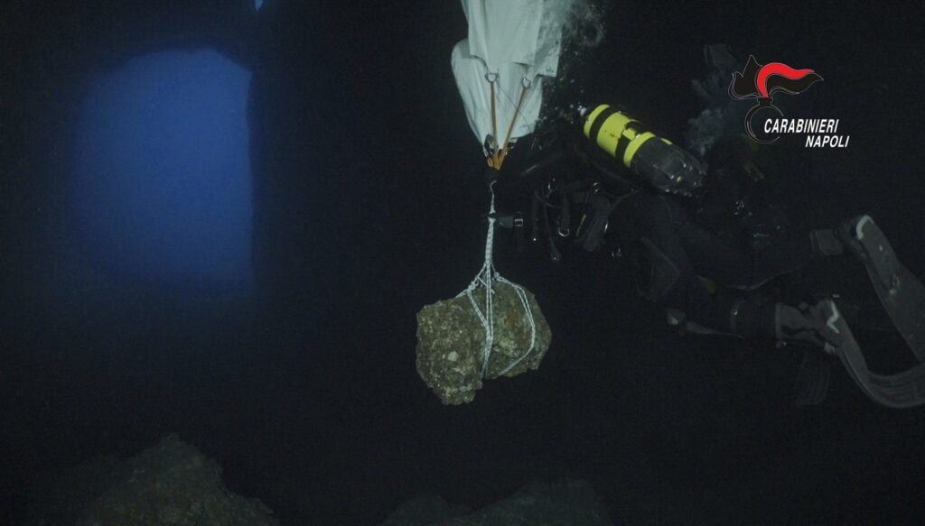 A police diver heads to the grotto entrance with the Roman marble relic