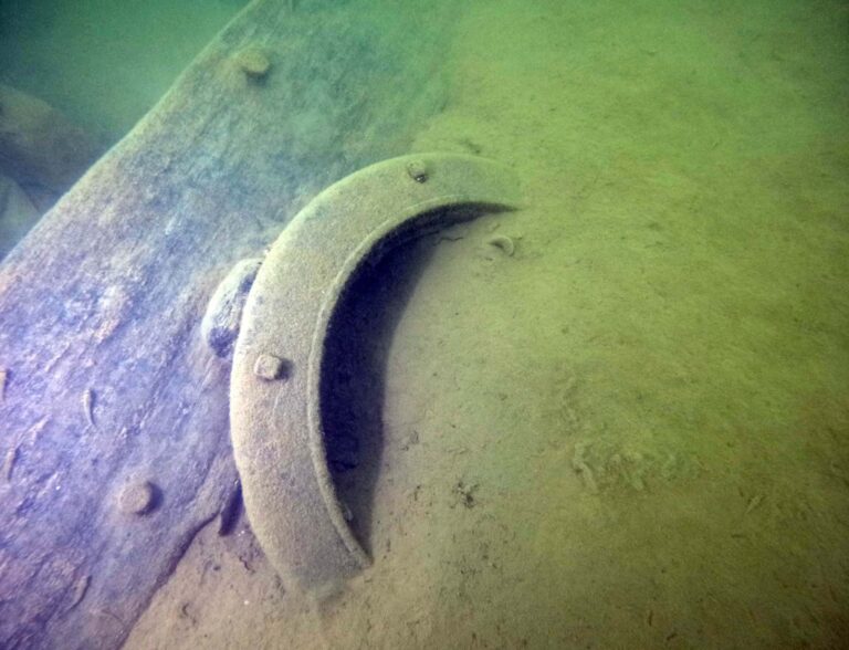 A porthole from the JC Ames tug protruding from the lake silt (WHS, Maritime Preservation & Archaeology Program)