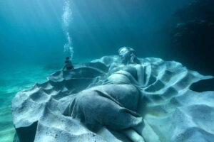 A diver dwarfed by Ocean Gaia (Jason deCaires Taylor)