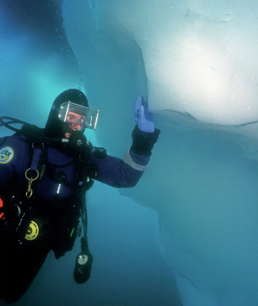 Iceberg Diving in Greenland: Beauty, Danger and Essential Safety Protocols 11 A diver feeling the smooth sides of a Greenland iceberg underwater