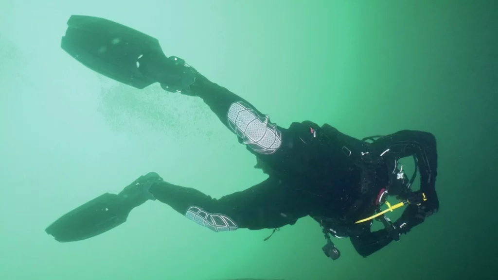 A technical diver in a drysuit performing a frog kick using Halcyon Vector Pro fins in a quarry.