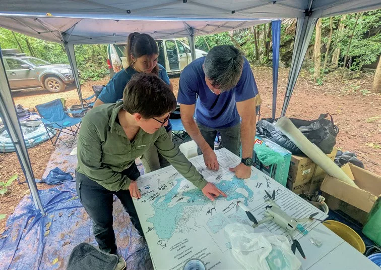 Technical divers and archaeologists discussing recovery strategies for ancient human remains at the Cave of Bones base camp.