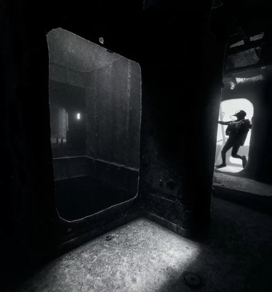 Q&A with Jennifer Idol: Diving Every 50 States 3 An atmospheric black and white underwater photo peering down a long, eerie corridor of a sunken ship.