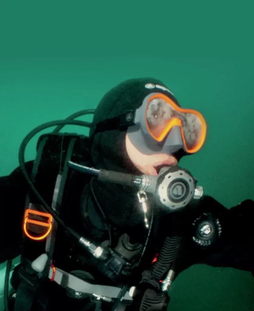 A diver navigating through green, low-visibility water, demonstrating proper buoyancy and control to avoid a common scuba problems.