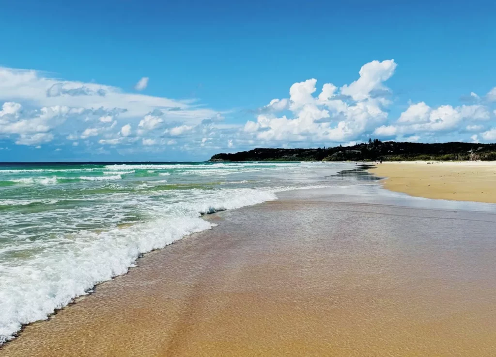 A beautiful stretch of white sand and turquoise ocean at a pristine beach on North Stradbroke Island, perfect for swimming and relaxing.