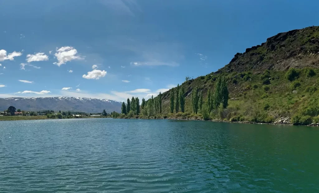 Scenic view of the turquoise waters of Lake Dunstan in Central Otago, surrounded by golden hills and mountains, providing a backdrop for freshwater diving.