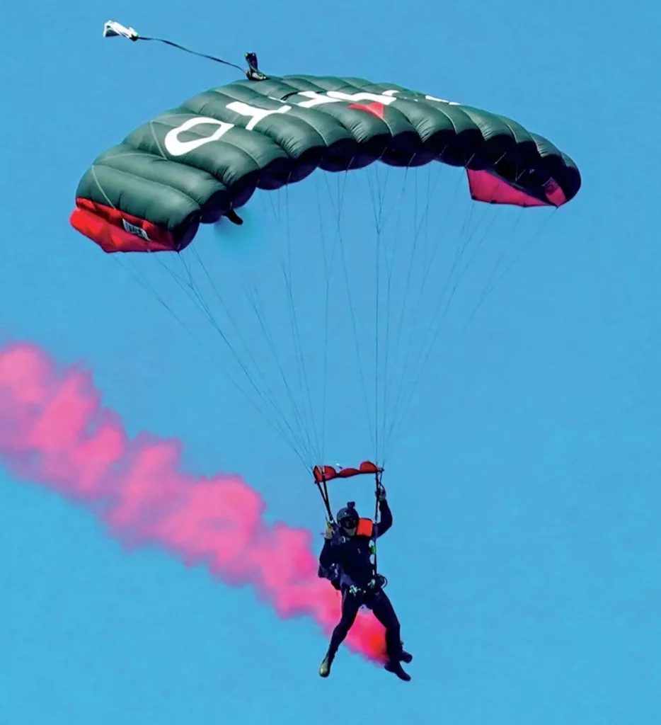 Professional skydiver Andy Torbet gliding over Spring Lakes with red smoke.