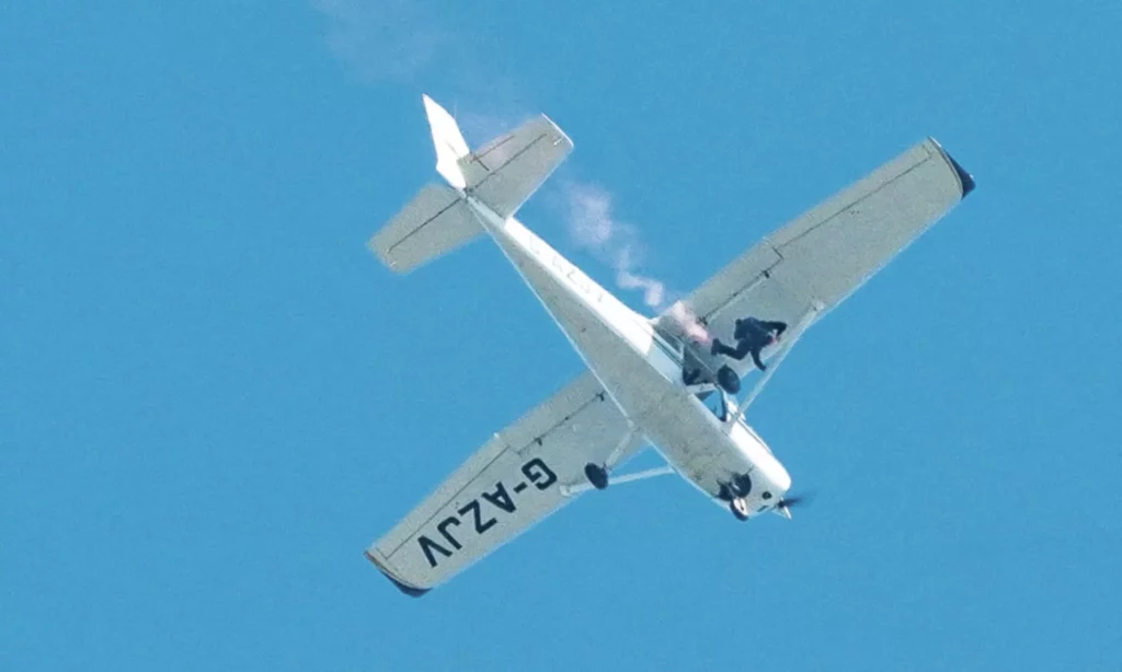 Andy Torbet exiting a plane wearing a scuba cylinder and skydiving rig.