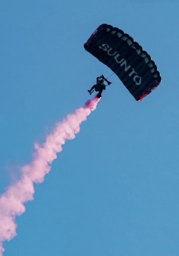 Skydiver trailing red smoke during the UK's first civilian skydive to scuba jump.