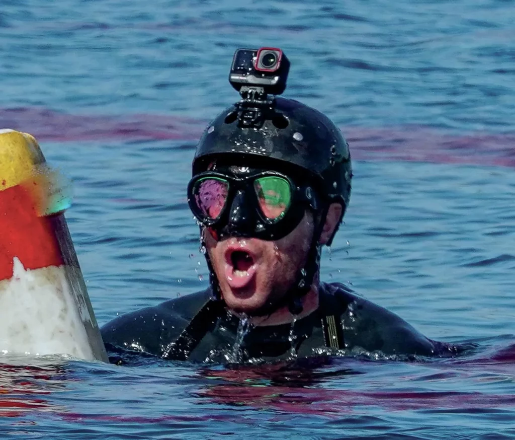Andy Torbet surfacing from a lake in scuba gear after parachuting in.