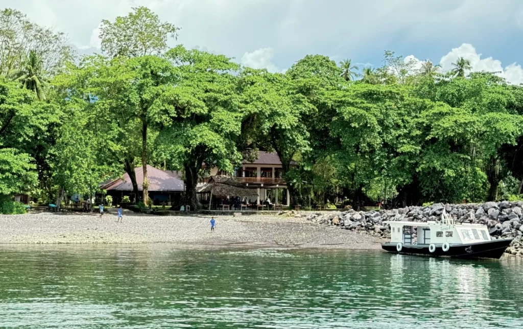 Murex Manado Resort dive boat anchored in calm tropical waters.