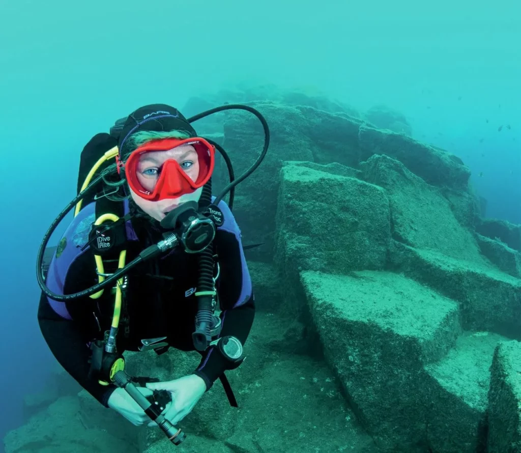 A diver posing against the dramatic underwater volcanic rock formations characteristic of the island.